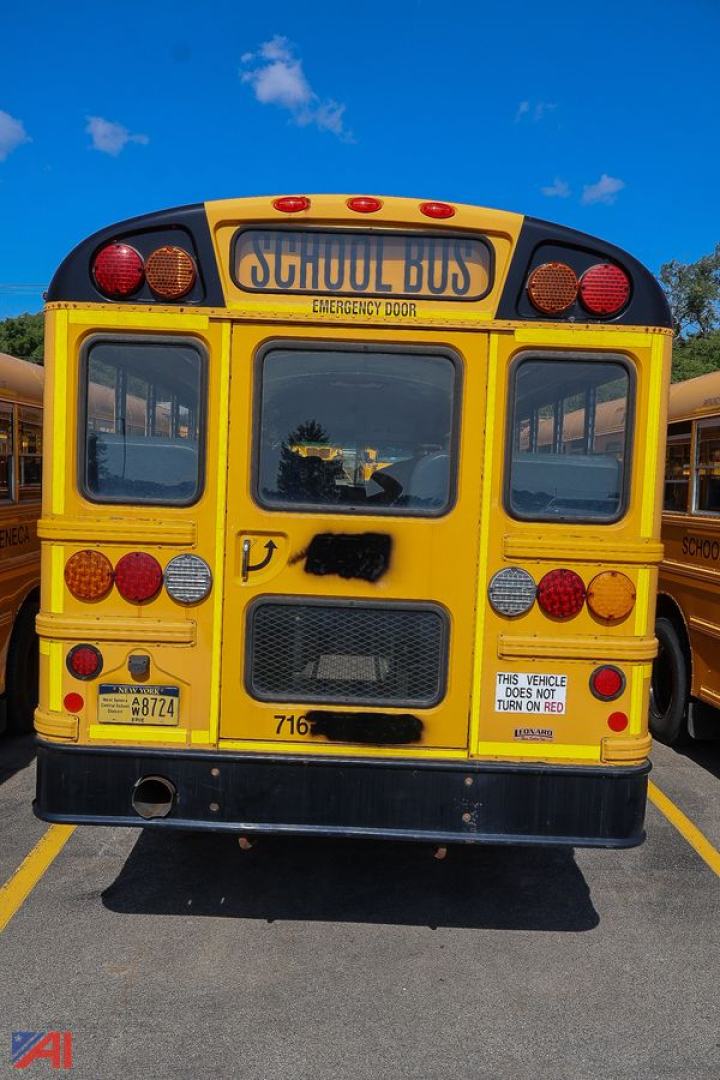 Back view of a yellow IC Corporation CE Series school bus with emergency exit, tail lights, and rear bumper visible.