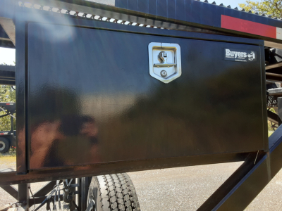 Truck trailer toolbox door with lock, side view showing Buyers sign, black metal surface and stair/ladder components.