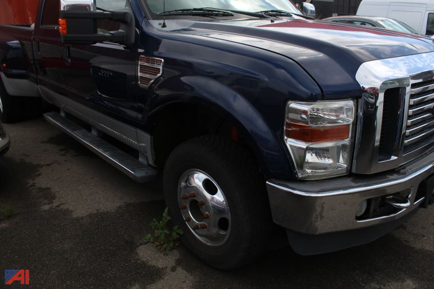 Ford F-350 Super Duty pickup truck front left wheel well and chrome bumper visible in a parts lot