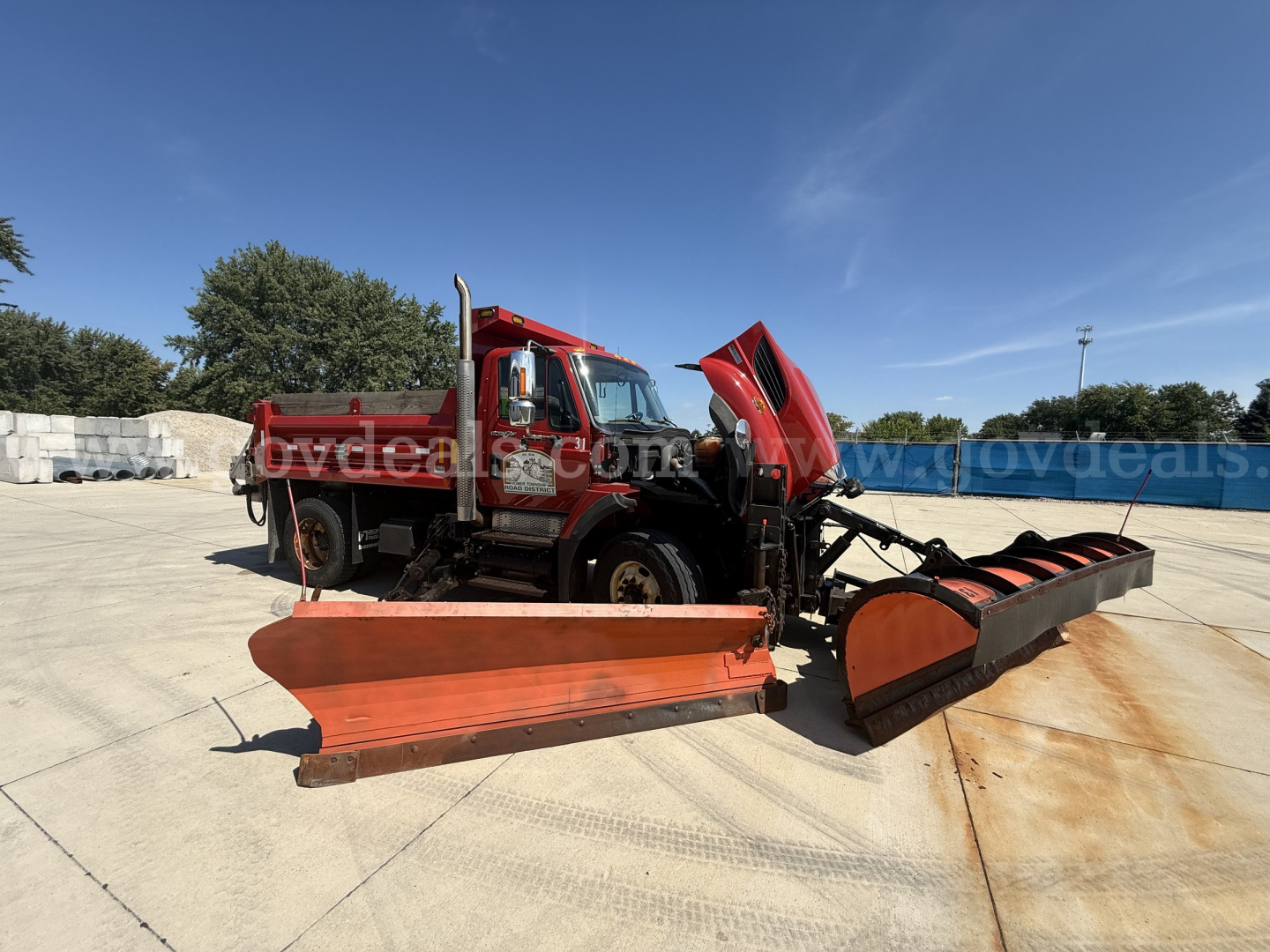 Dump truck with snow plow attachment and equipment in front view showing International 7400 cab and front bumper.