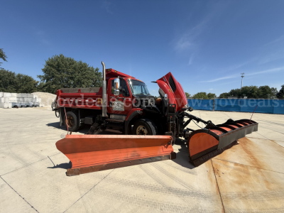 Dump truck with snow plow attachment and equipment in front view showing International 7400 cab and front bumper.