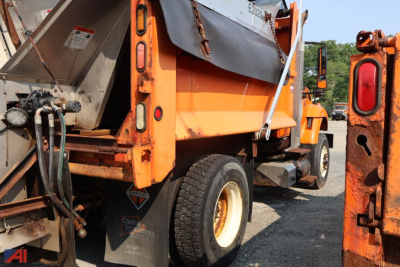Dump truck bed and rear wheel area of a 2014 International WorkStar 7400 dump truck showing orange body, hydraulic lines, and warning labels.