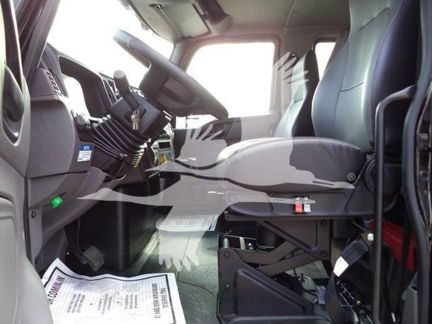 Truck cab interior of a 2027 International MV showing driver's seat, steering wheel, dashboard, and pedals.