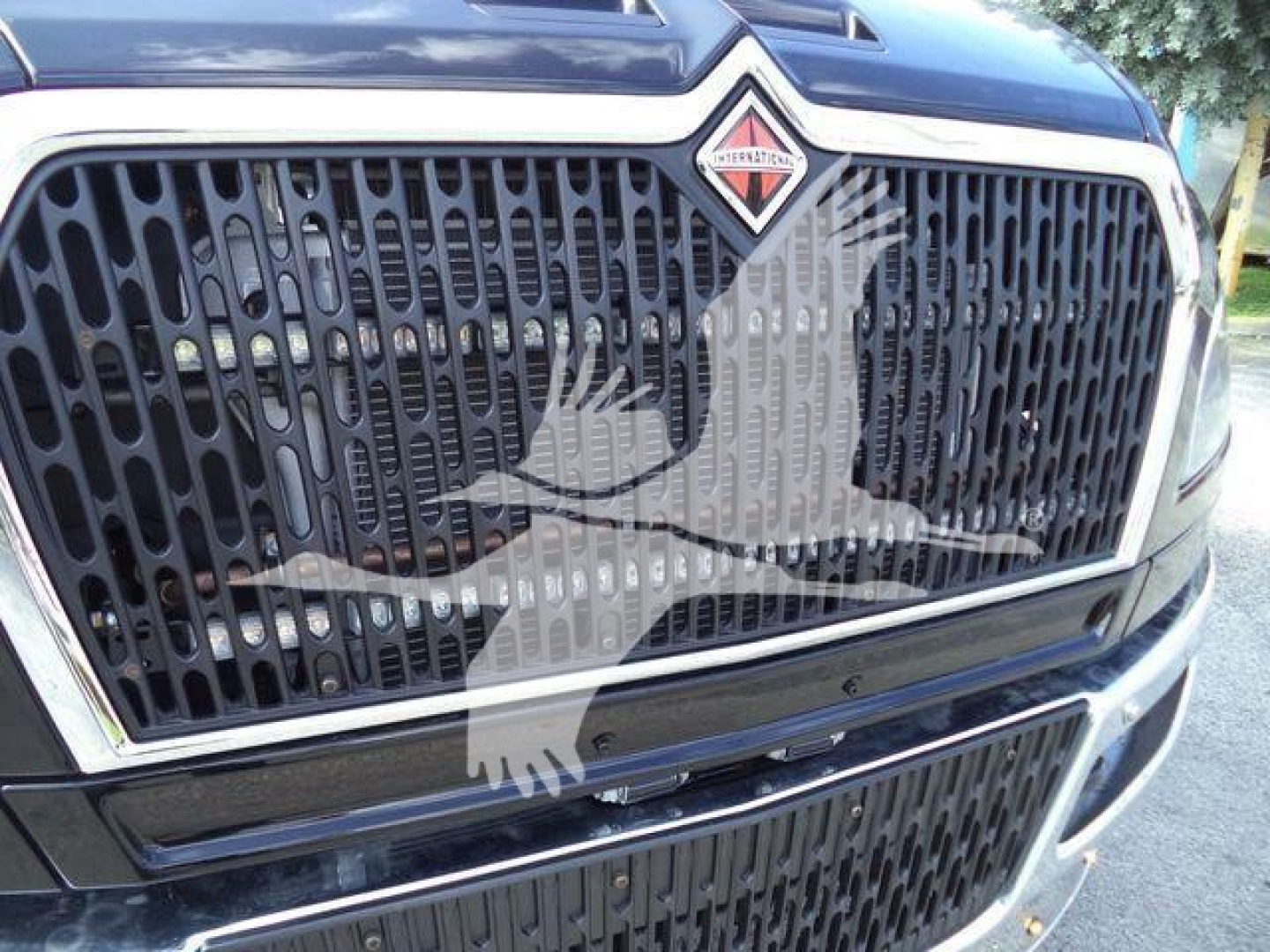 Front grille of a 2027 International MV truck showing the large black honeycomb grille and the International badge on the hood.