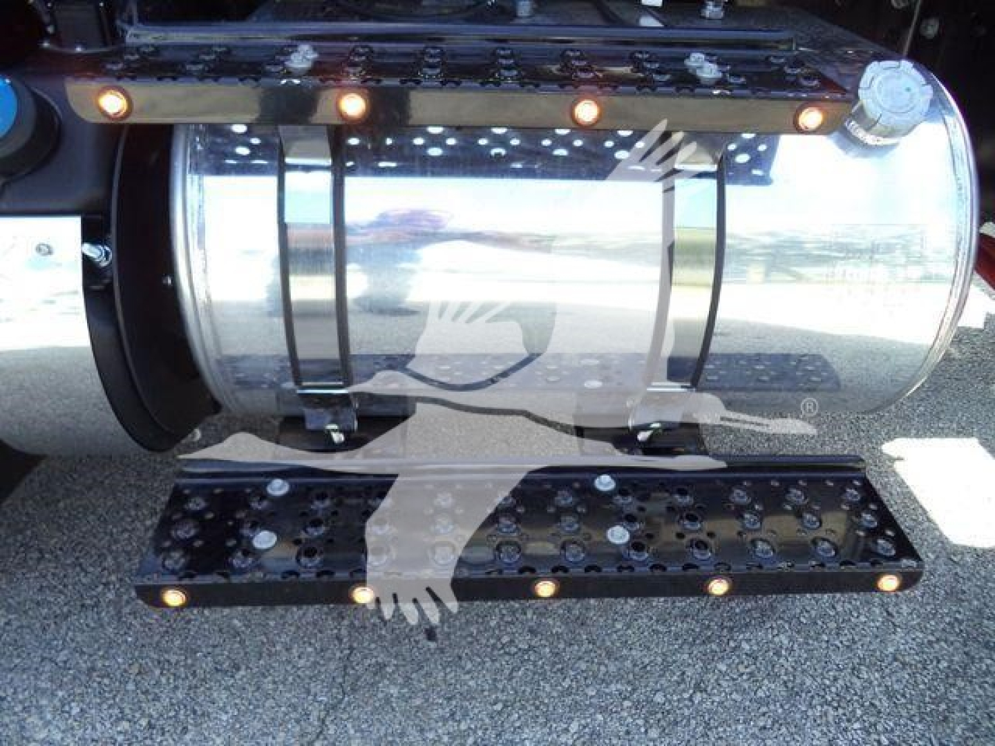 Tractor-trailer fuel tank and metal steps showing chrome tank and black steps with multiple bolts and lights.