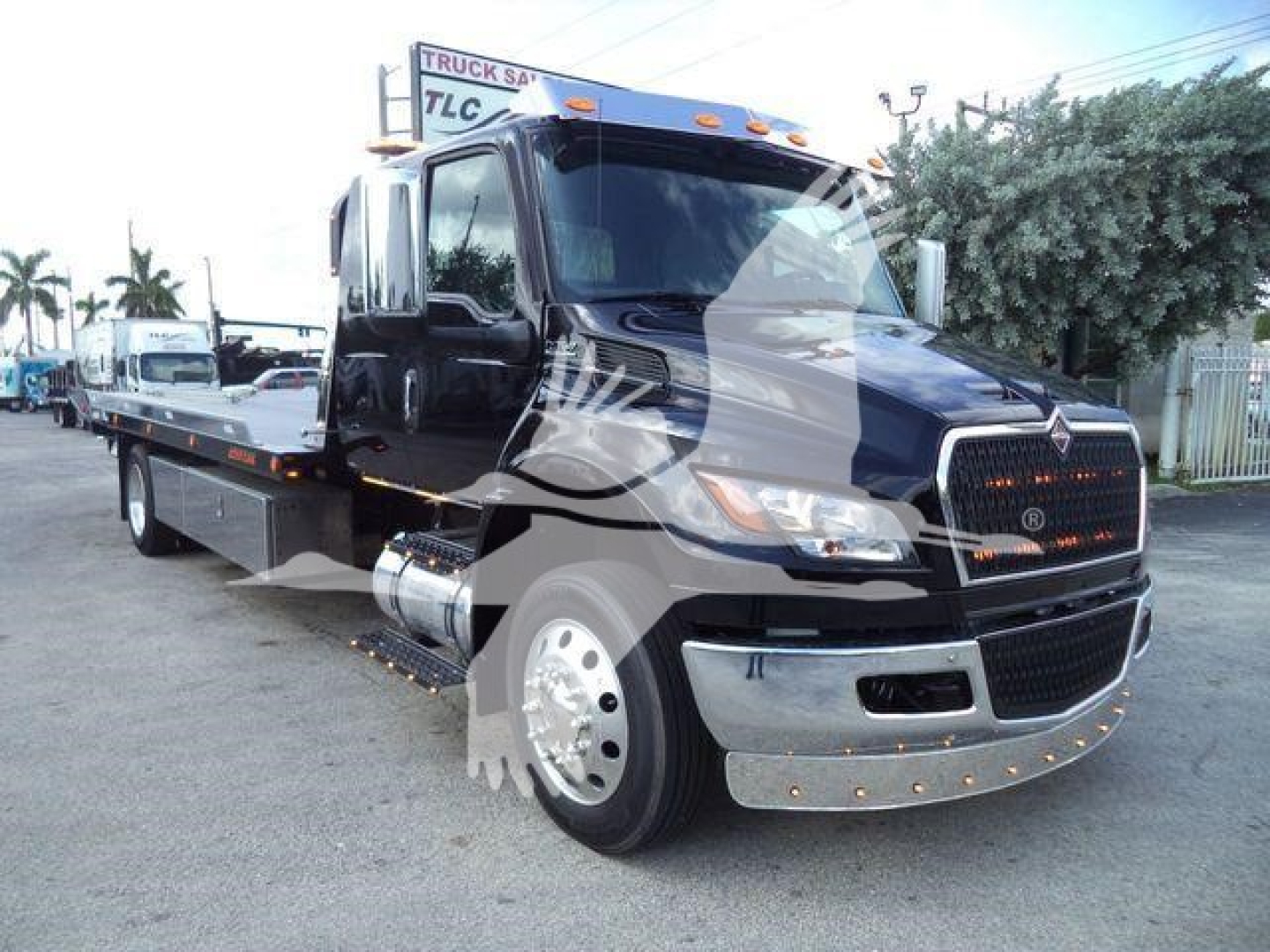 Truck showing 2027 International MV rollback w/ flatbed and chrome front bumper, black cab, side mirrors, and orange marker lights.