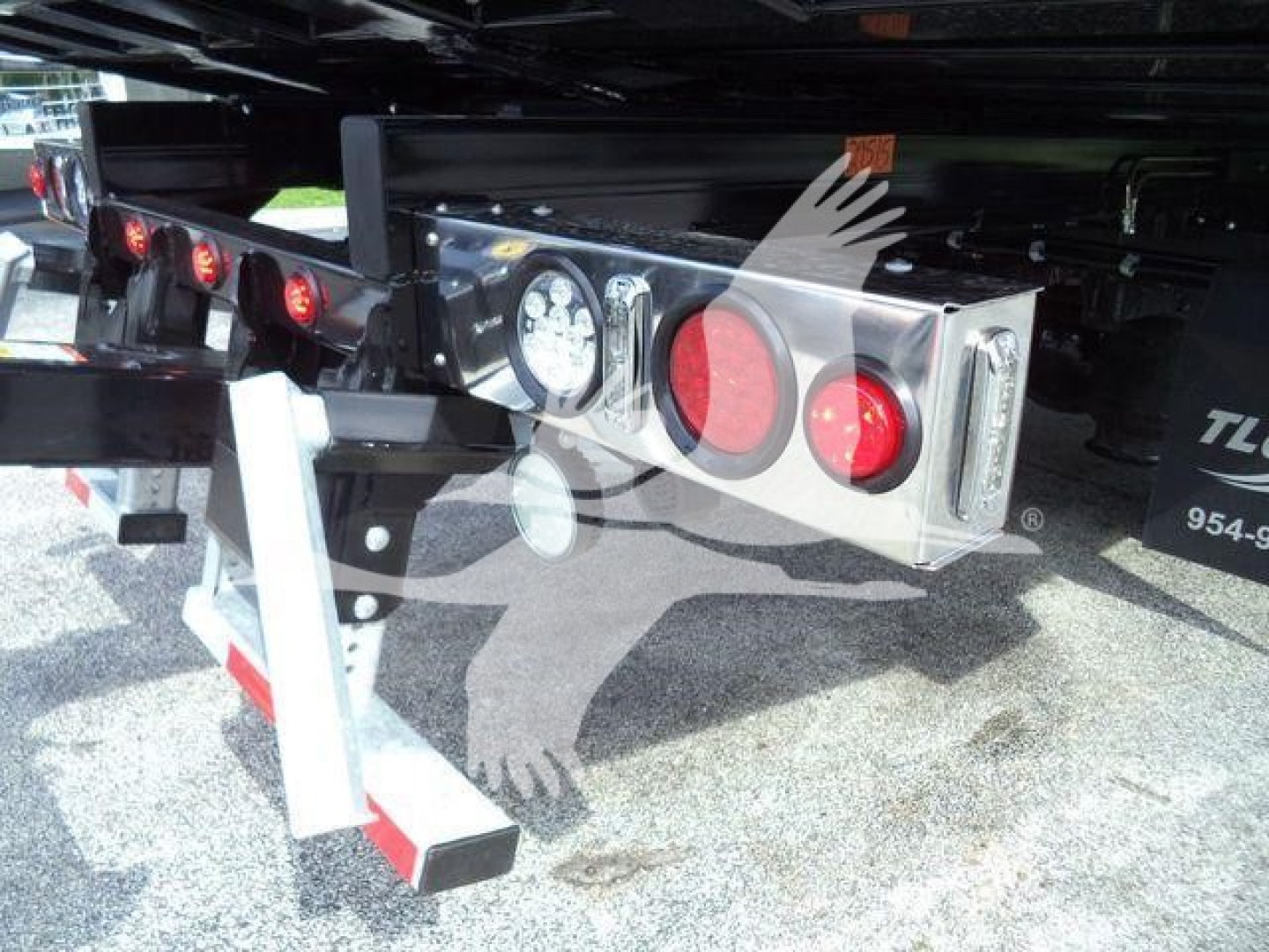 Rear view of a 2027 International MV rollback truck showing bumper-mounted lights, dual red taillights, and platform undercarriage with reflectors.
