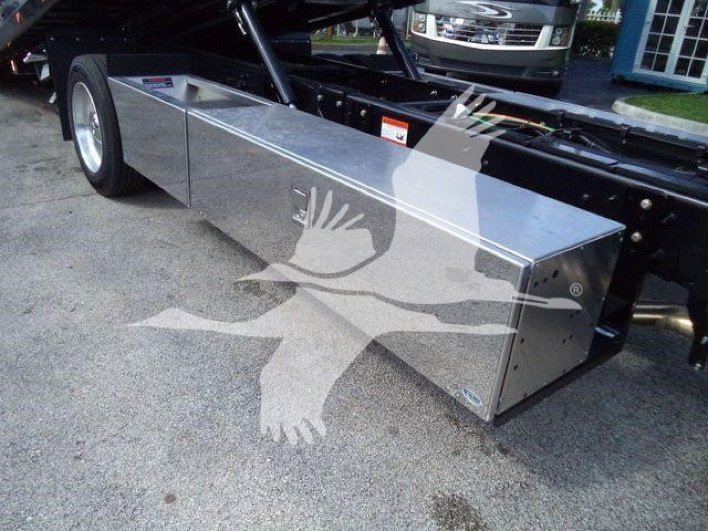Aluminum toolbox/storage box mounted under a truck frame with a silver finish and riveted panels.