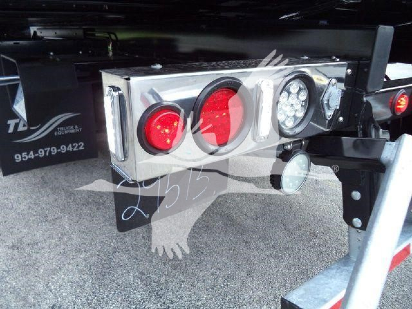 Trailer rear lighting package with red and white tail/marker lights and a license plate/reflector area mounted on a steel frame showing a chrome toolbox and mounting hardware.