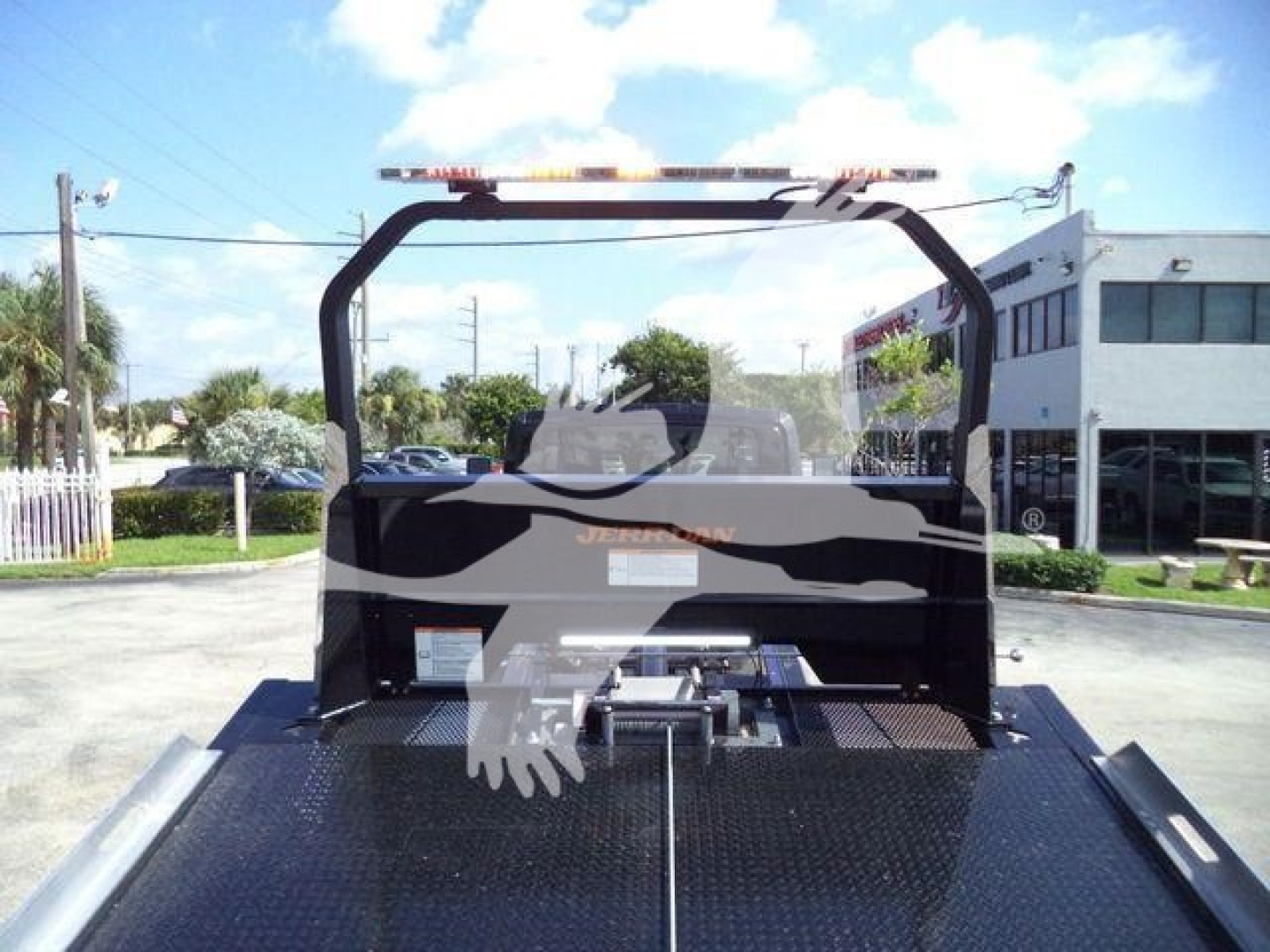 Truck bed of a 2027 International MV rollback truck showing a black rollover frame and rear platform with warning lights on top.