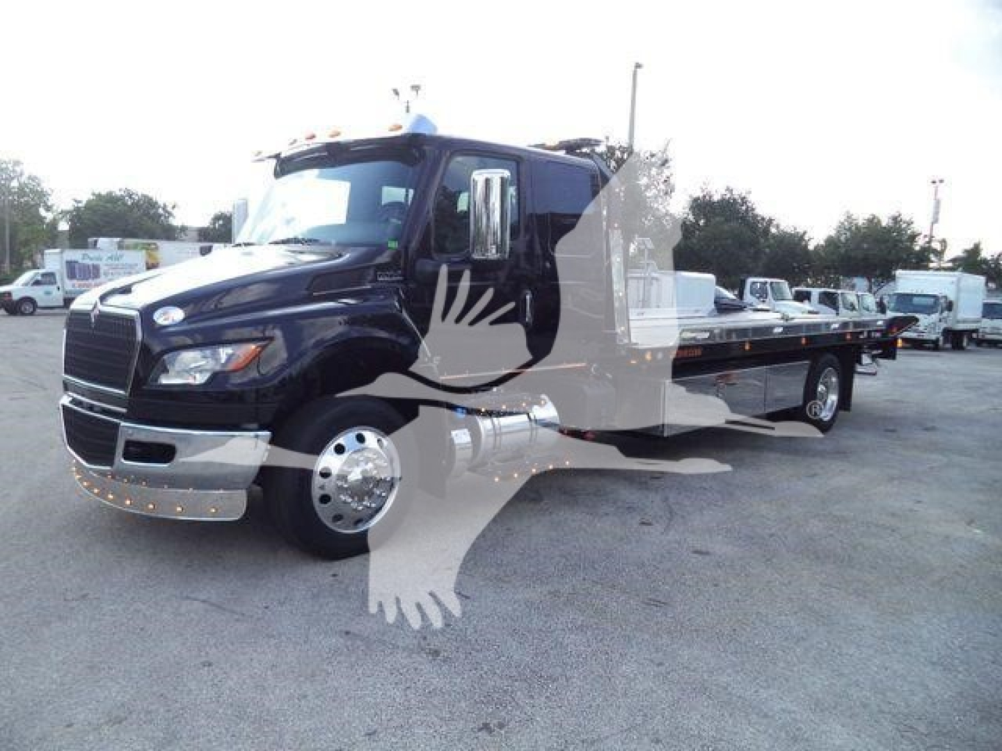 Truck: 2027 International MV rollback tow truck in black, front and side views visible with extended flatbed; chrome front bumper, dual rear wheels, large mirrors.