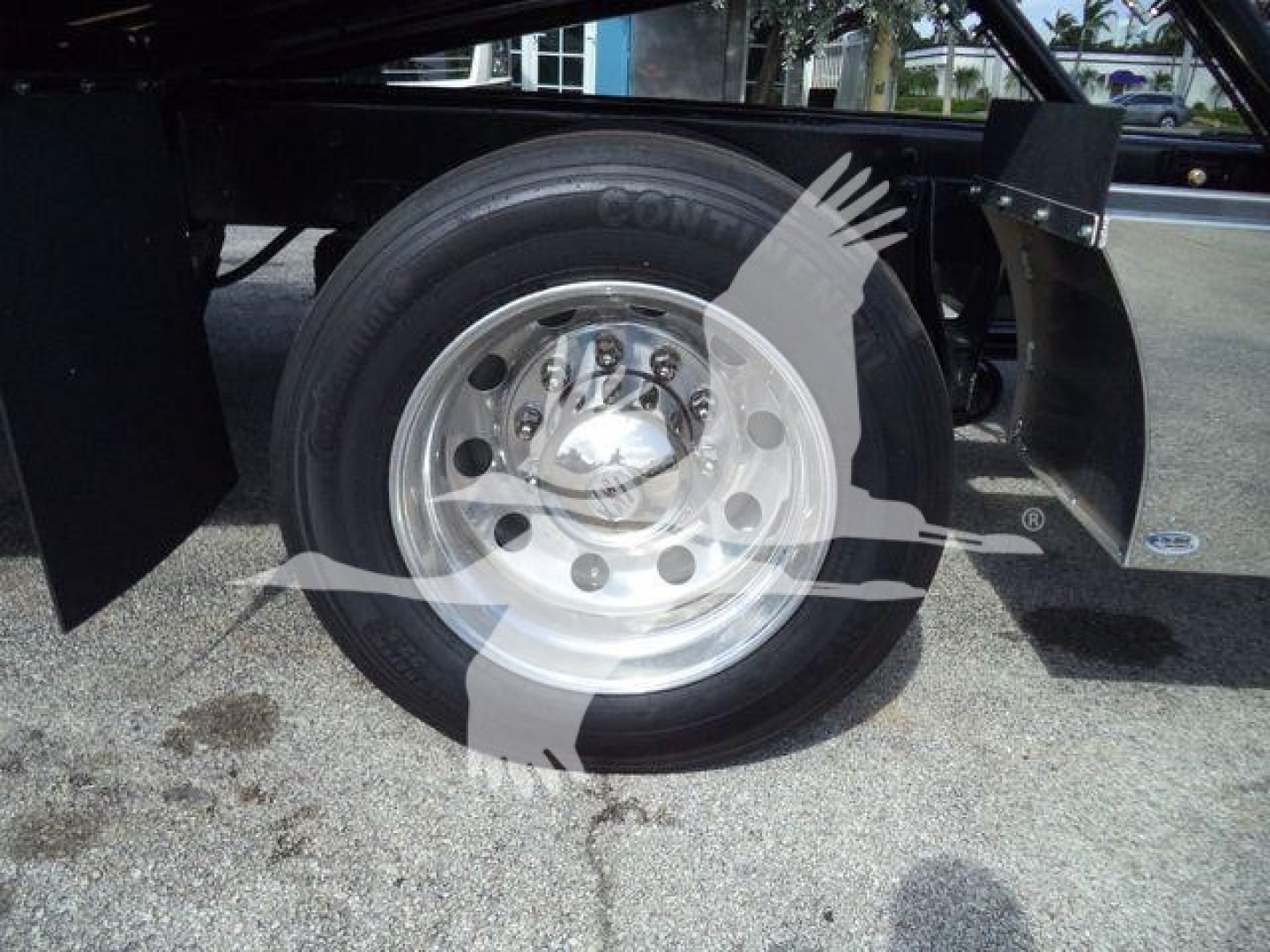 Truck wheel and front suspension view showing a radial tire mounted on a polished steel rim.