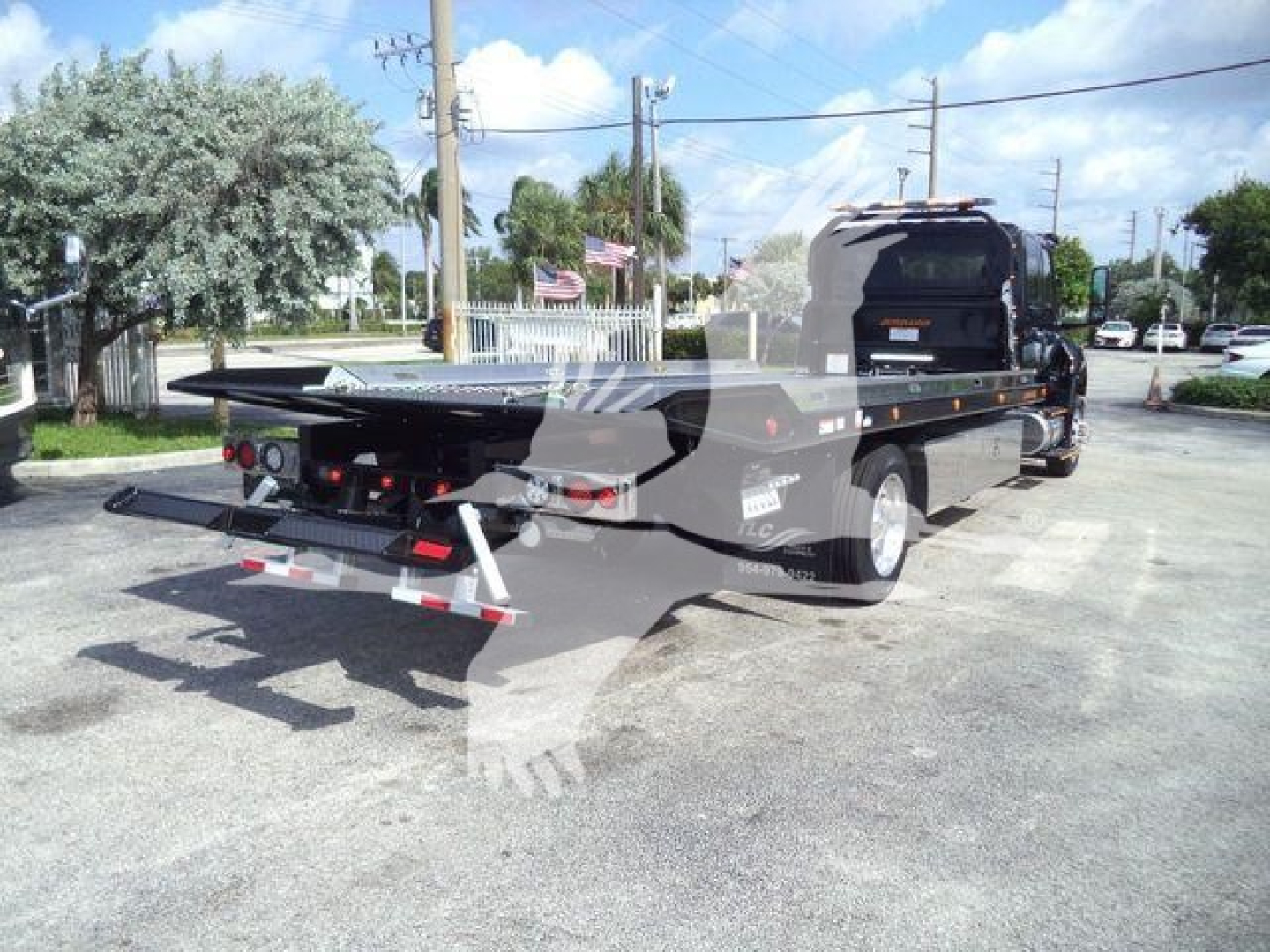 Flatbed tow truck in a lot showing MV607EXCAB22ITD stock number and rollback category.
