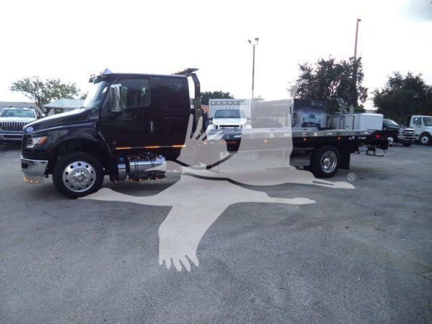 Truck with a flatbed in a dealership lot showing a black cab and long wheelbase flatbed. Visible text on the stall indicates MV607EXCAB22ITD stock number.