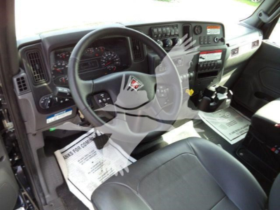 Truck cab interior showing steering wheel and dashboard with gauges and controls in an International MV cab.