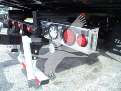 Rear view of a 2027 International MV rollback truck showing bumper-mounted lights, dual red taillights, and platform undercarriage with reflectors.