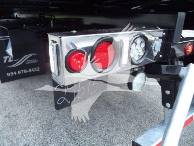 Trailer rear lighting package with red and white tail/marker lights and a license plate/reflector area mounted on a steel frame showing a chrome toolbox and mounting hardware.