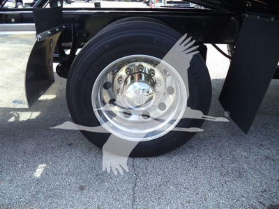 International MV truck wheel and chrome rim showing front axle and tire, with black chassis and mudguard visible.