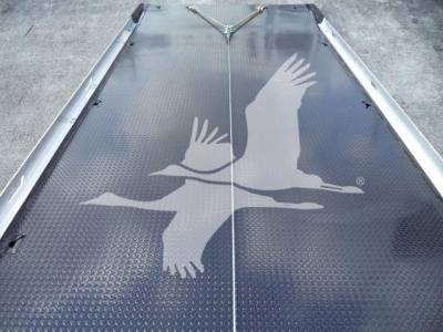 Platform deck with textured black diamond plate showing a large white graphic of two flying birds in formation, with a seam in the middle and a chain secured at the top.