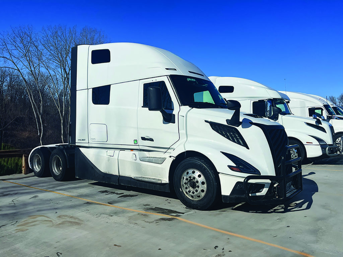 Volvo VNL 860 sleeper cab truck in white, side view showing front grille, dual rear axles, and aerodynamic mirrors.