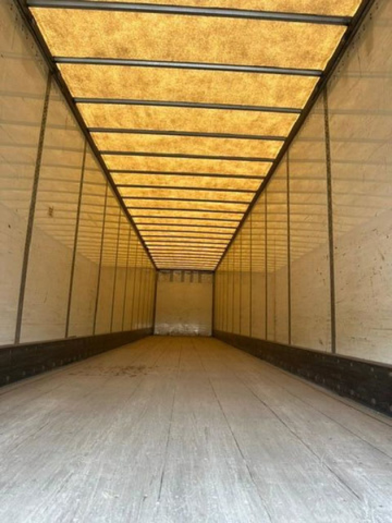Interior of a 2013 Wabash van trailer cargo area, long empty space with wooden roof panels and side walls, illuminated by natural light.