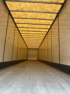 Interior of a 2013 Wabash van trailer cargo area, long empty space with wooden roof panels and side walls, illuminated by natural light.