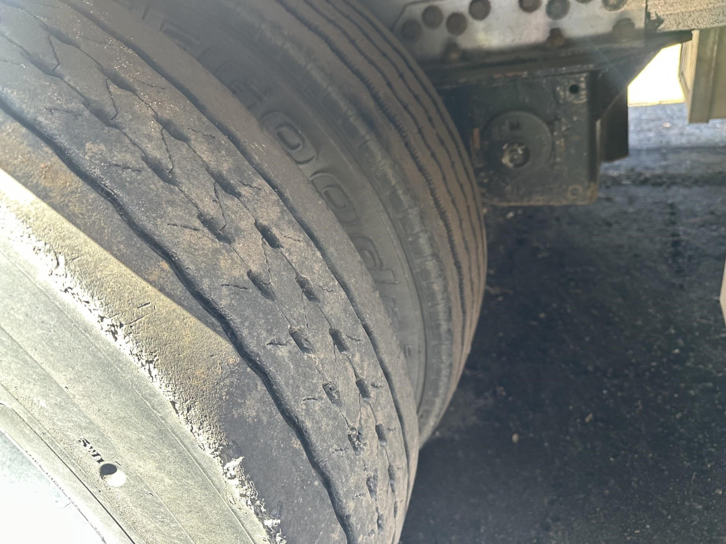 All-aluminum drop deck trailer wheel/axle view showing dual tires and suspension components.