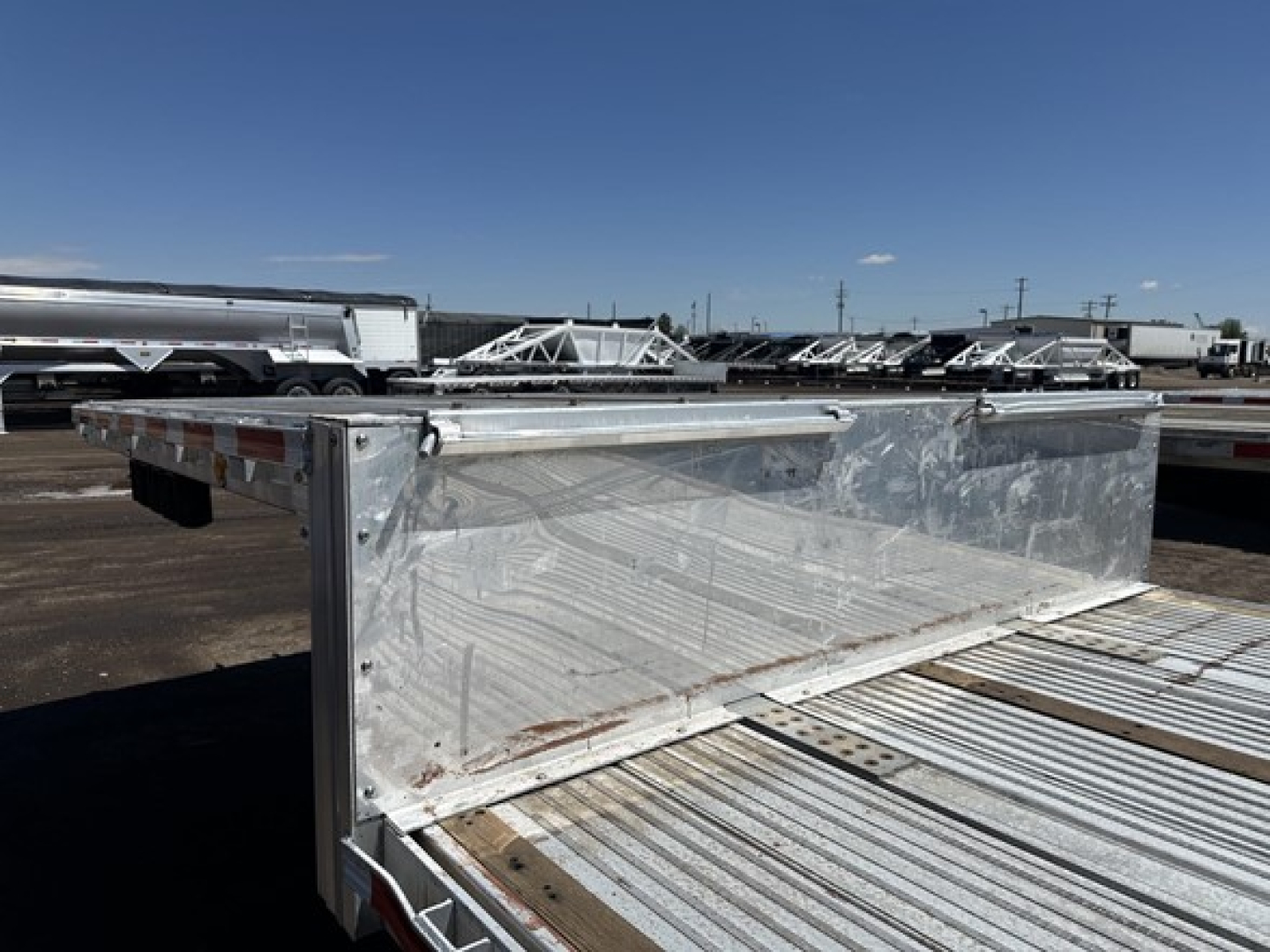 All-aluminum drop deck trailer with rear ramps and boxes showing solid metal construction and reflective surfaces.