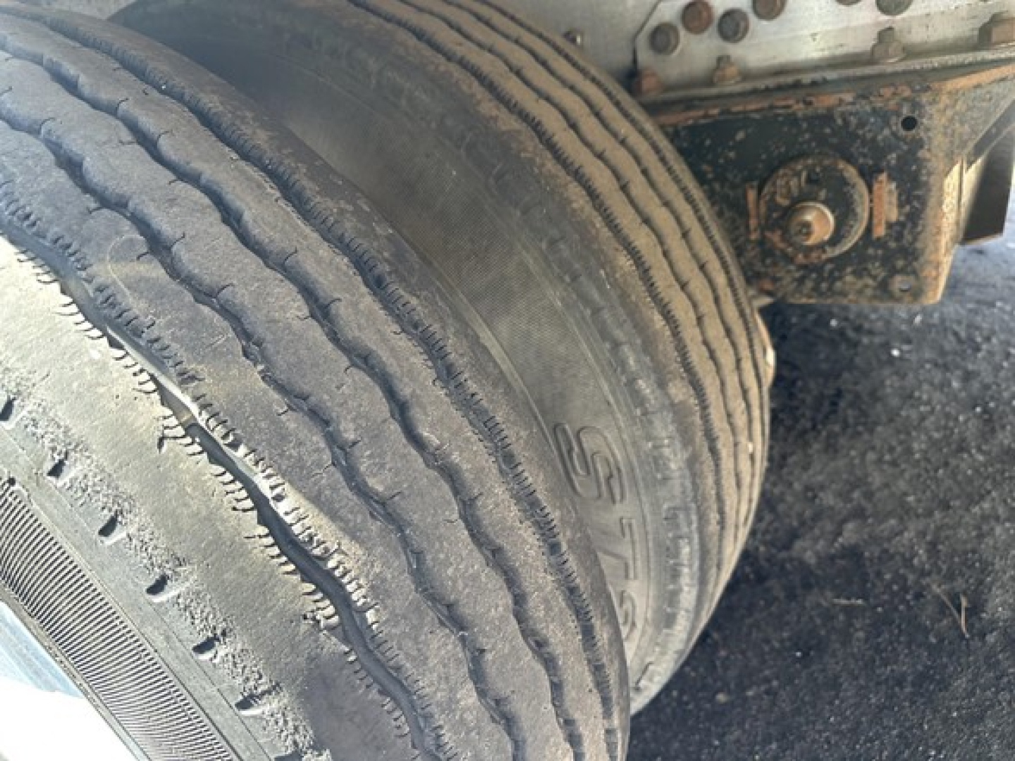 Truck trailer tire and undercarriage showing dual rear wheels and suspension components.