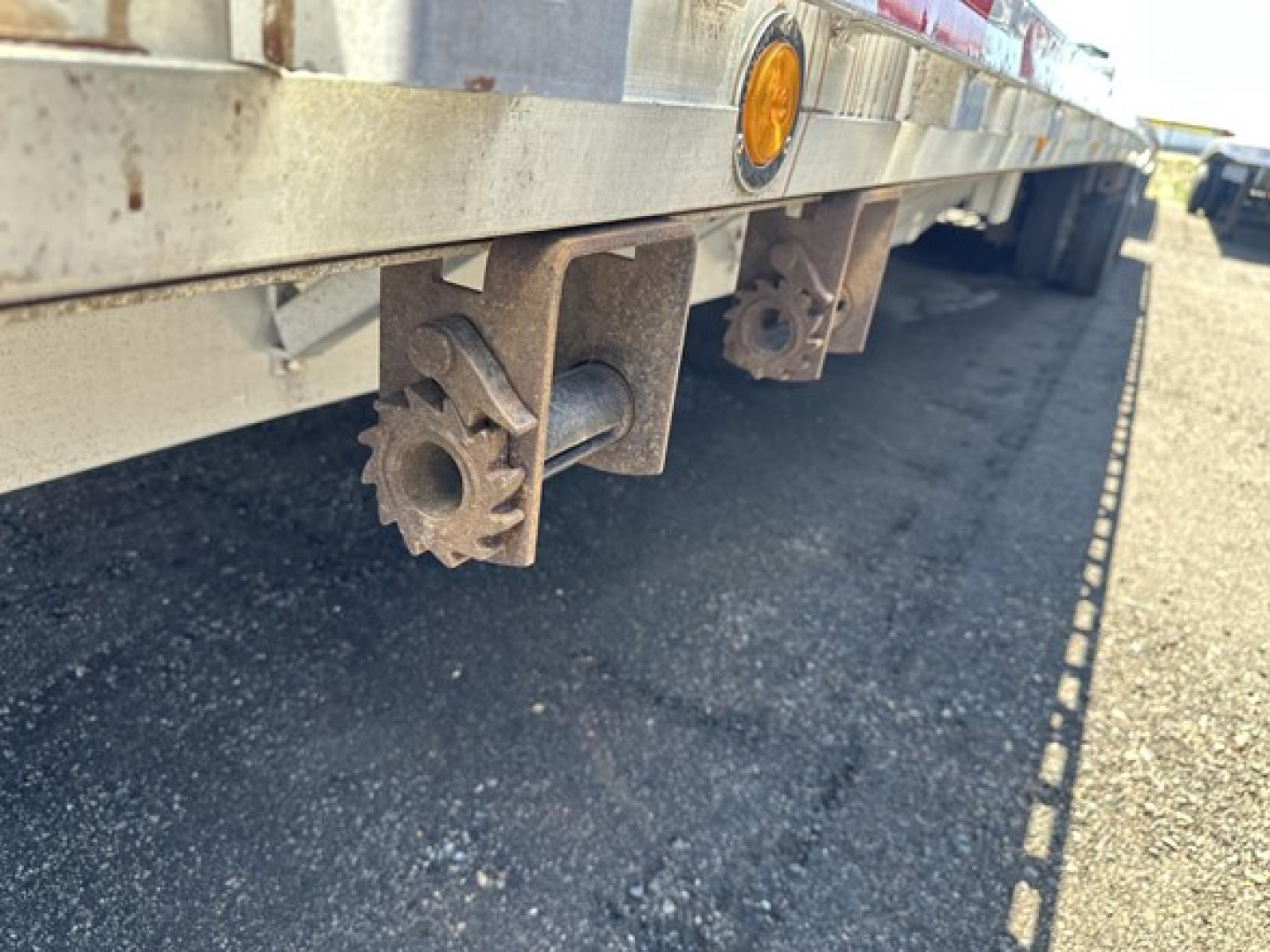 Trailer undercarriage view showing rail gear and mounting brackets on aluminum drop deck trailer.