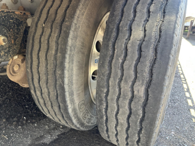 All-aluminum drop deck trailer wheels and tires viewed from the side showing dual axles and tread patterns.