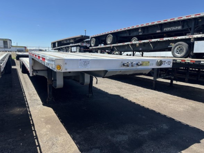All-aluminum drop deck trailer showing 48 ft deck with two tool boxes and 4 ramps; frontend area and side markers; some printed text visible on the side rail.