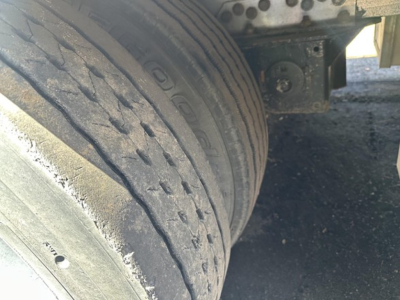 Trailer wheel and undercarriage detail showing tire treads and suspension area of a 2014 Reitnouer drop deck trailer.
