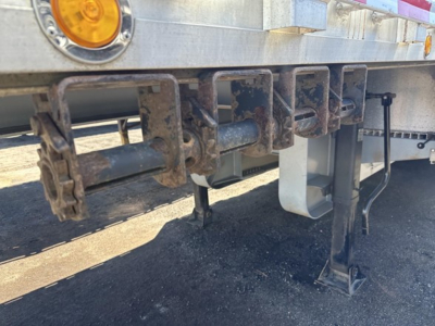 Drop deck trailer undercarriage showing multiple chain/sling hooks and support legs with steel framework.