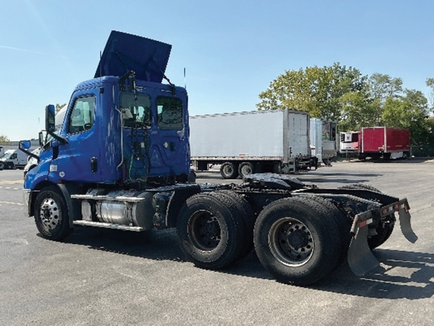 Truck chassis view of a blue 2019 Freightliner Cascadia 116 used daycab with rear dual axles and exposed fifth wheel, in a lot.