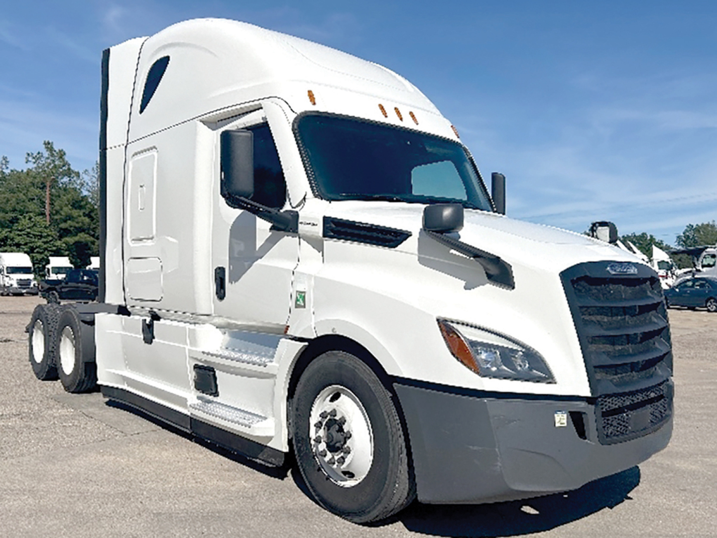 Truck side view of a white 2022 Freightliner Cascadia 126 tractor in a lot, with sleeper cab and black grille