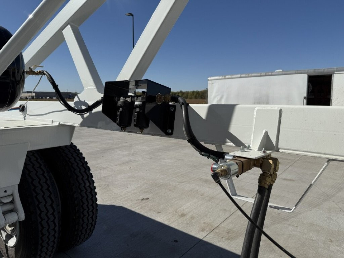 Trailer hitch and hydraulic arm on Armor Lite SBD40 skeleton dump trailer showing hydraulic hose, brass coupling, and frame.