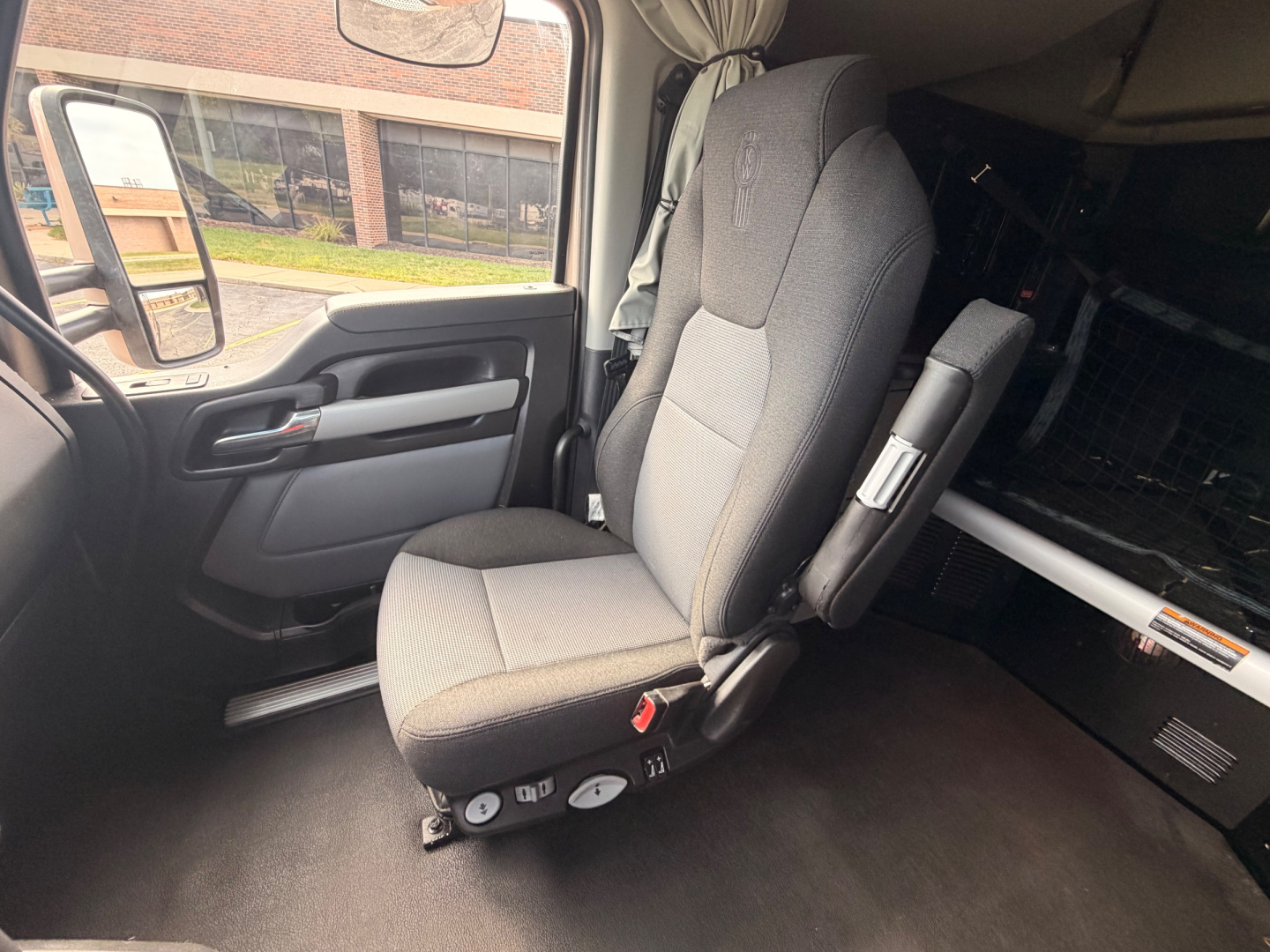 Kenworth T680 truck interior seat and part of cab, driver seat with controls, window and door panel visible