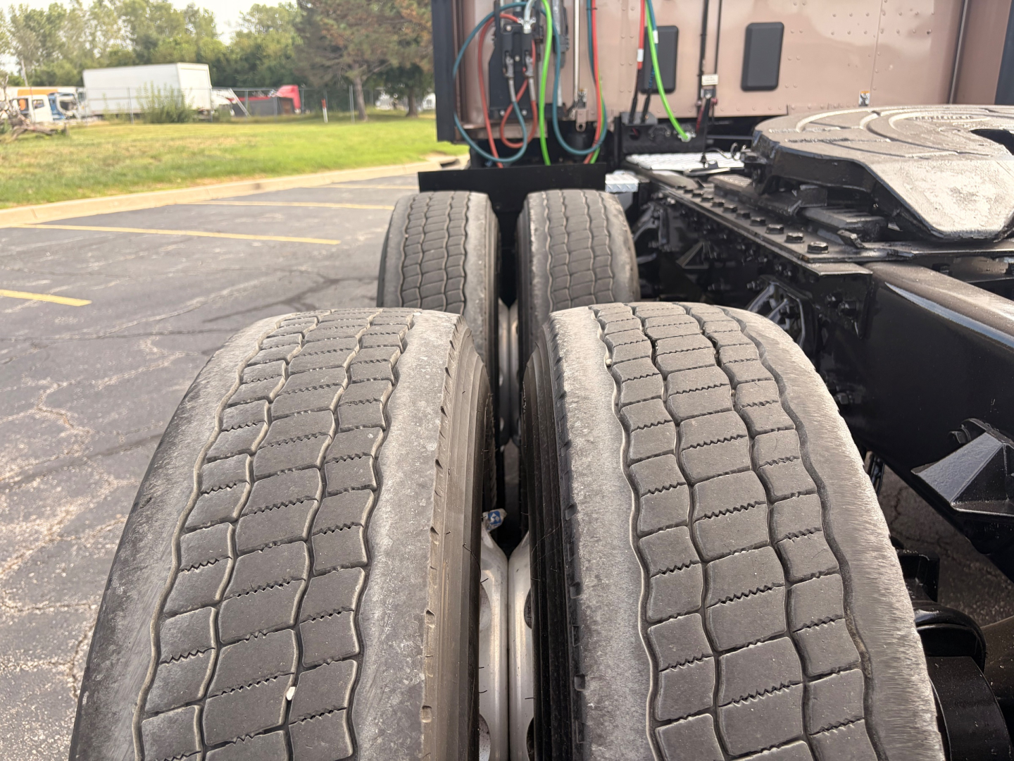Kenworth T680 truck rear dual axle view showing rear tires and wiring harnesses in cab area.