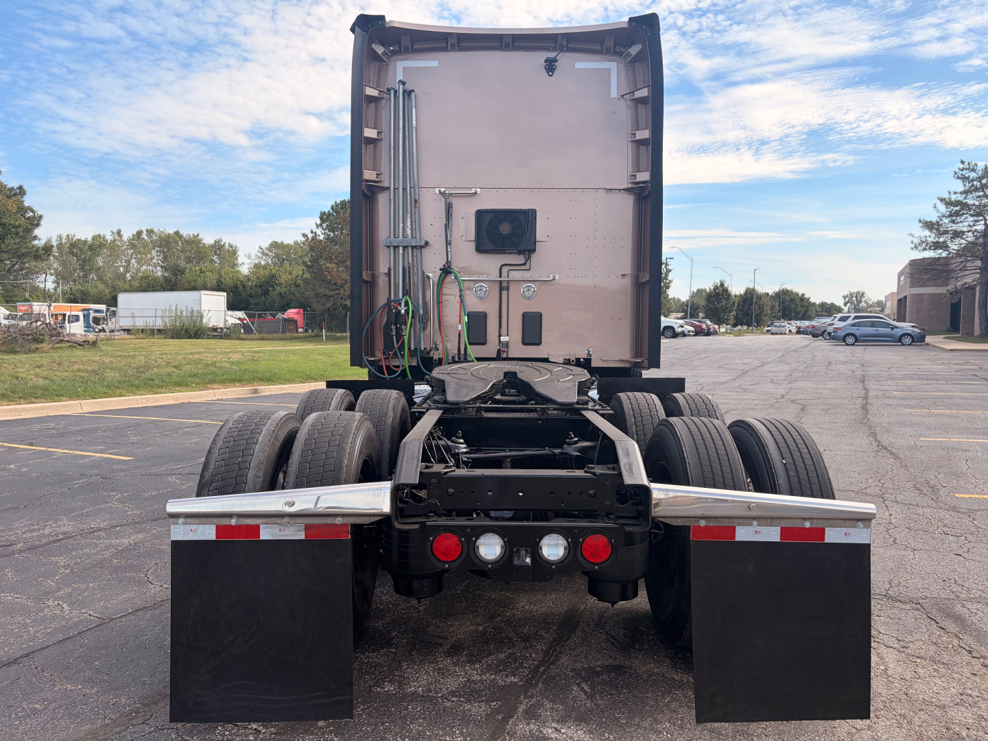 Kenworth T680 rear view showing fifth wheel area and dual rear axles with mud flaps and wiring harnesses visible in sleeper cab truck.