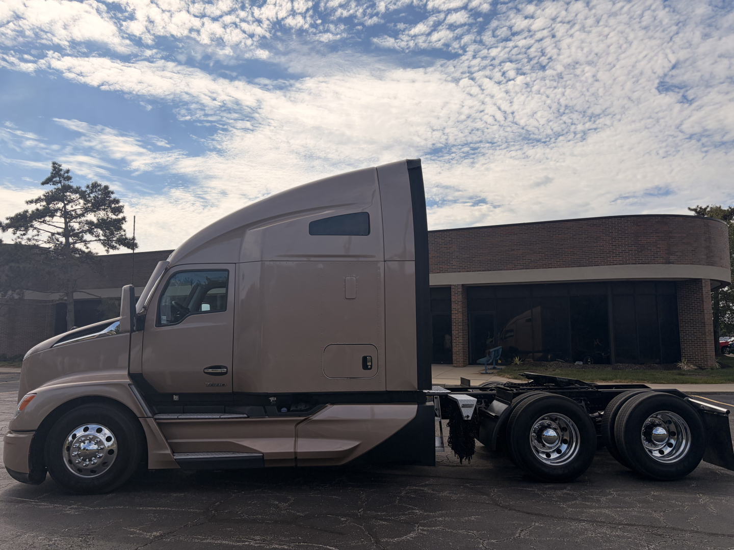 Kenworth T680 conventional sleeper truck side view showing dual rear axles and cab high-roof with beige color and chrome wheels.