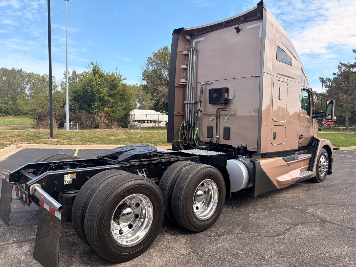 Kenworth T680 sleeper tractor rear and side view showing triple rear axles and fifth wheel area with wiring and components mounted on the back of cabin.