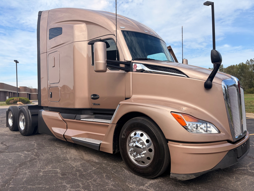 Kenworth T680 sleeper cab tractor in tan showing front and side, chrome wheels, aerodynamic mirrors.