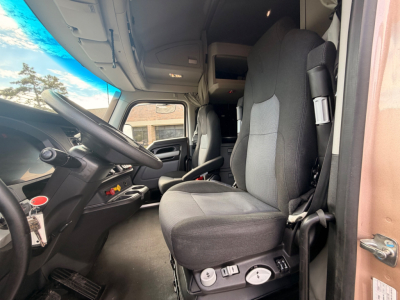 Kenworth T680 truck interior: driver seat with controls, steering wheel, dashboard, and cabin bunk area visible from open door.