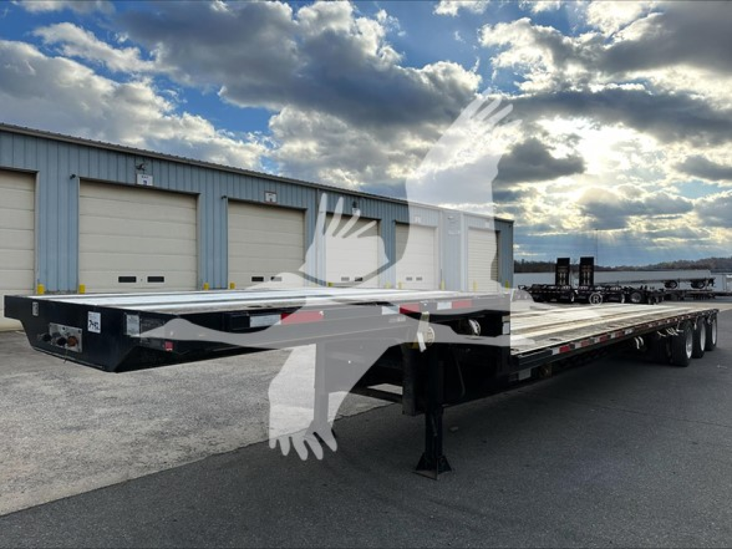 Flatbed trailer with three-axle extendable bed showing DT2000 Transcraft model and VIN and stock plate in front area.