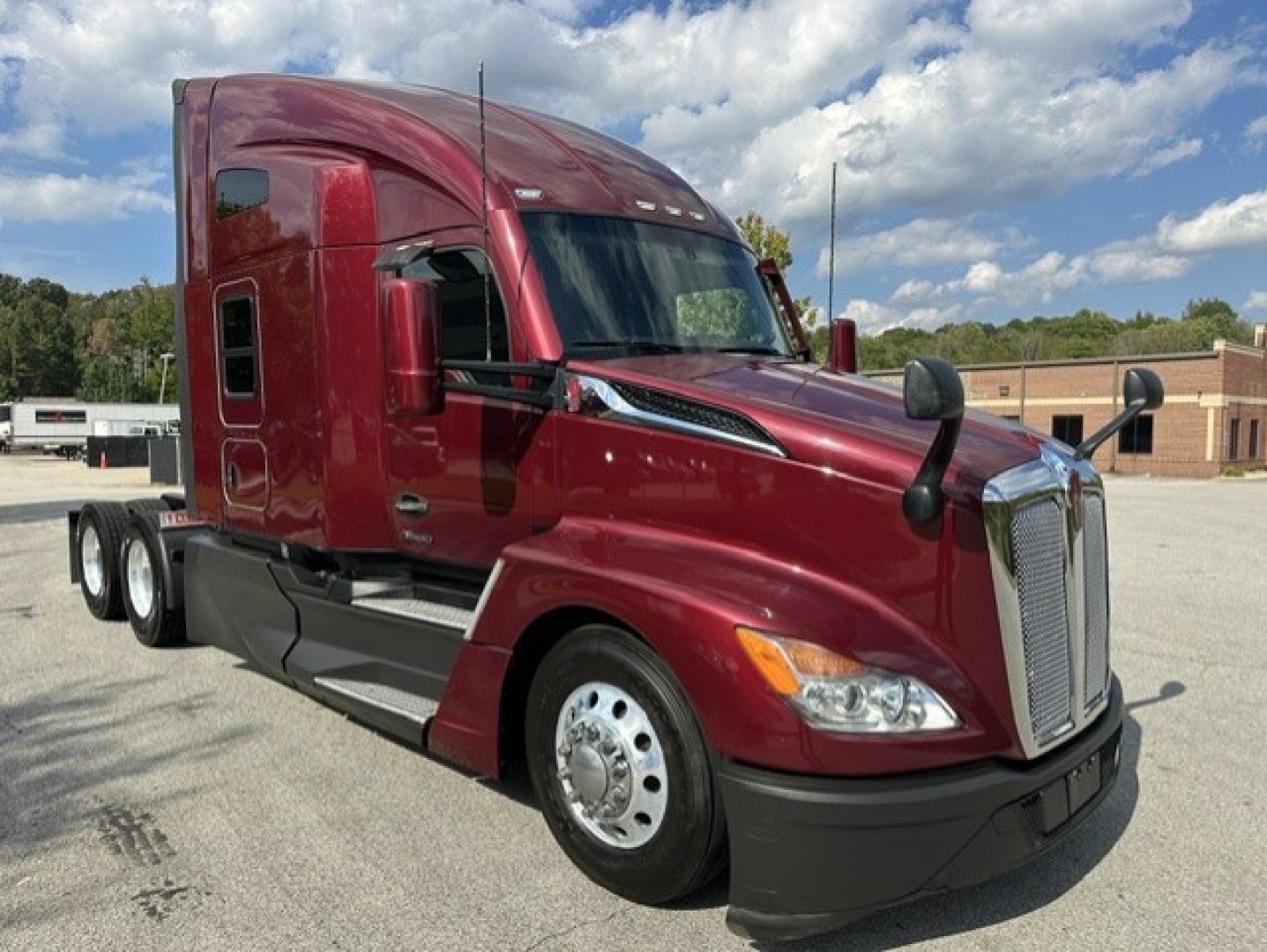 Kenworth T680 tractor-trailer cab in maroon shows cab front with grille and headlights.