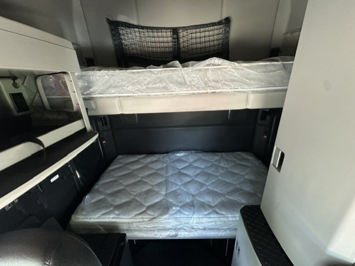 Kenworth T680 sleeper cab interior showing bunk beds with mattresses and side storage. View highlights upper and lower sleeping berths inside cab.