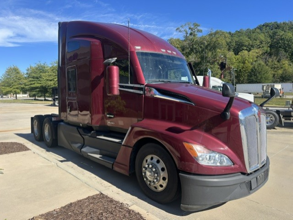 Kenworth T680 heavy truck in maroon color, front three-quarter view, with sleeper cab, two exhausts, and large grille; no visible text readable on components.