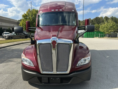 Kenworth T680 front view showing large chrome grille with Kenworth emblem, maroon cab, black bumper, side mirrors, and windshield; no readable specific model text visible on image.
