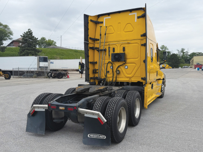 Freightliner Cascadia 126 rear view showing tractor with yellow cab and dual rear axles, fifth-wheel and mudflaps visible.